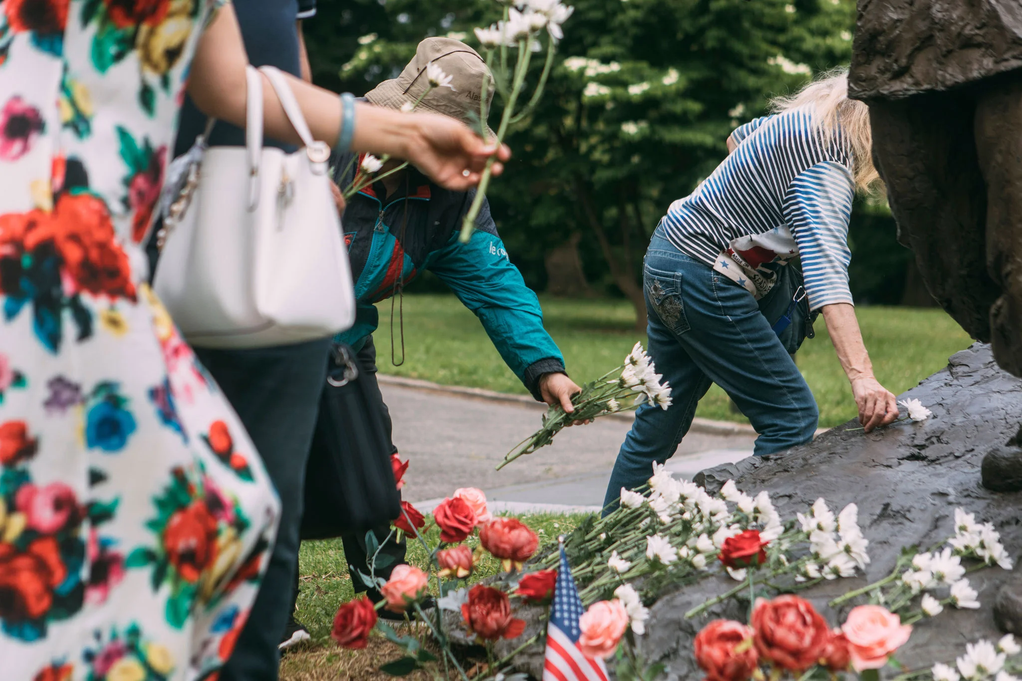 Four people place flowers at the base of the Korean War Memorial in Kissena Park