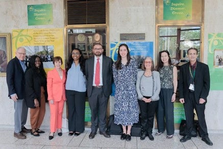 Group of people standing in a row with two doors and posters in the background