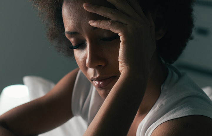 A black woman, eyes closed, looks distressed.
                                           
