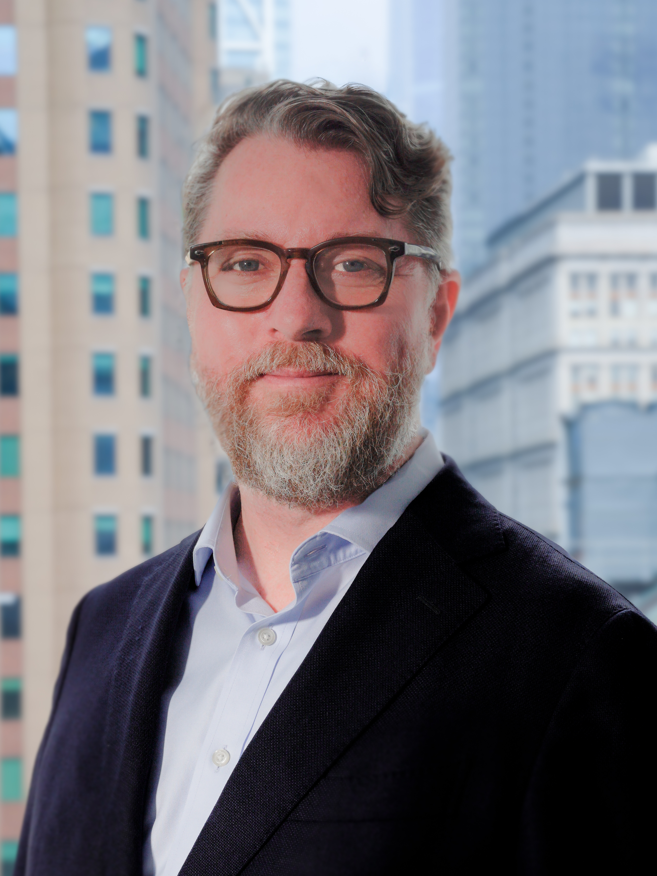Portrait of a Aaron Yarbrough in a black suit and glasses, smiling for a photo