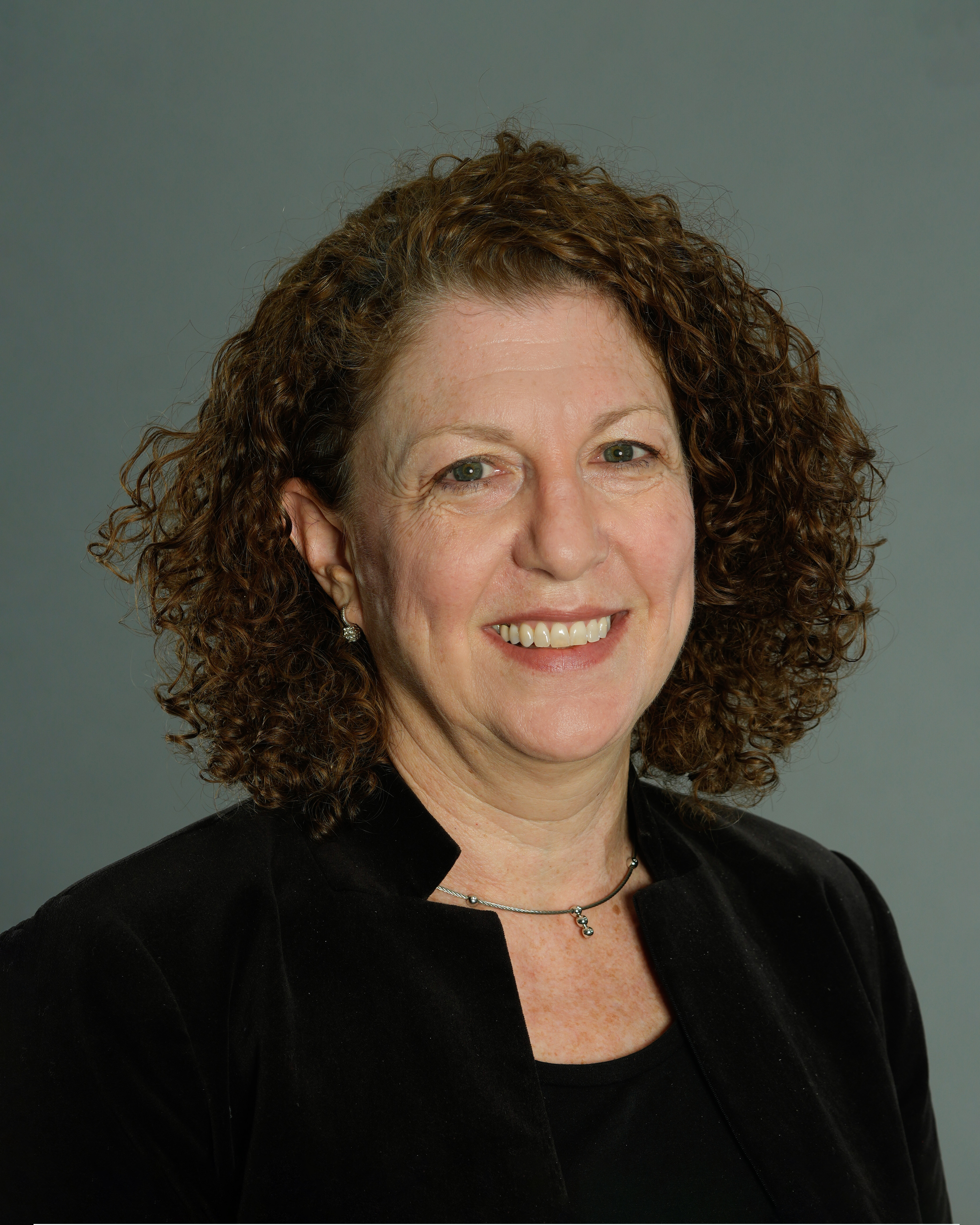 Portrait of Nancy Ginsburg in a suit, smiling for a photo