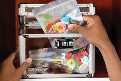 A hand placing a bag of cannabis edibles into a lockbox