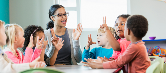 Woman is holding her hands up as children are counting with their fingers up