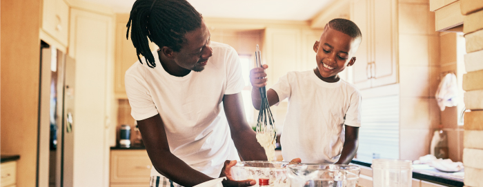 Adult and child playing in the kitchen with cooking utensils