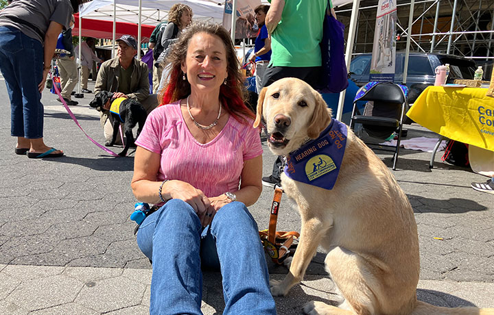 a woman is sitting down with her service dog
                                           