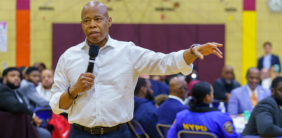 Mayor Eric Adams speaking with a microphone to community members at the East Flatbush Community Conversation