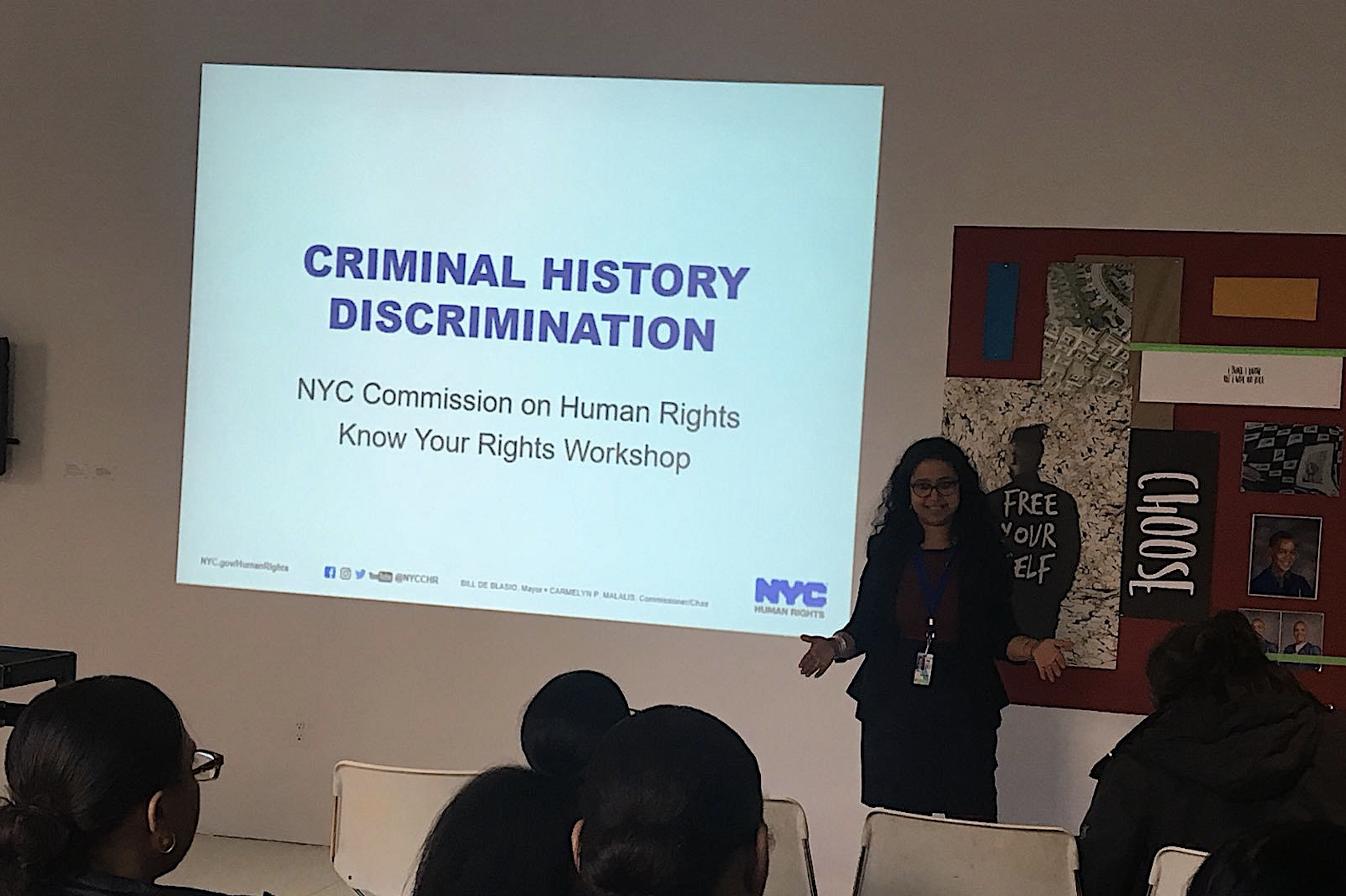 A Commission staff member speaking to a room of people with a presentation projection titled “Criminal History Discrimination : NYC Commission on Human Rights, Know Your Rights Workshop” projected on the wall behind her.