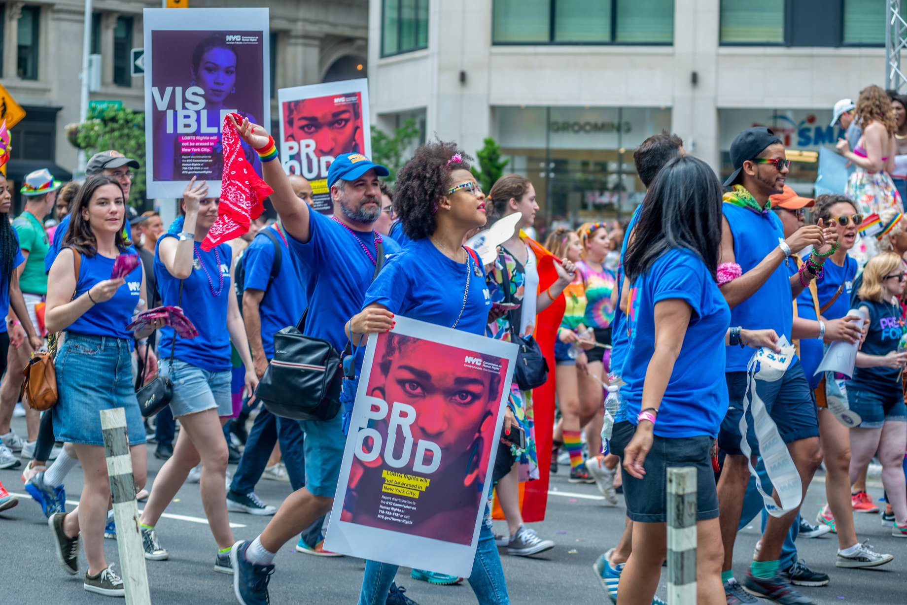 Several members of Commission staff marching at parade with signs that read “Visible” and “Proud.”