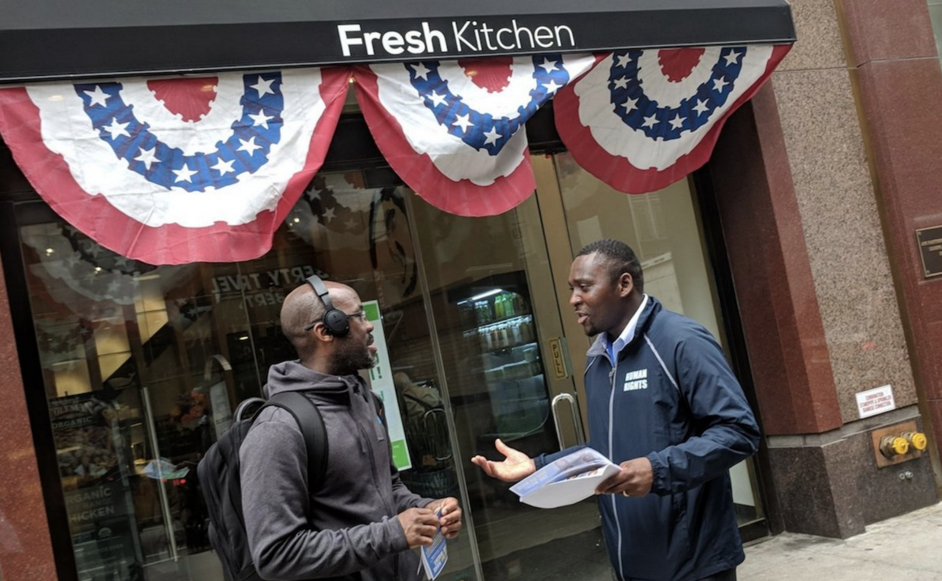 Commission staffer talking with community member in front of Fresh Kitchen restaurant.