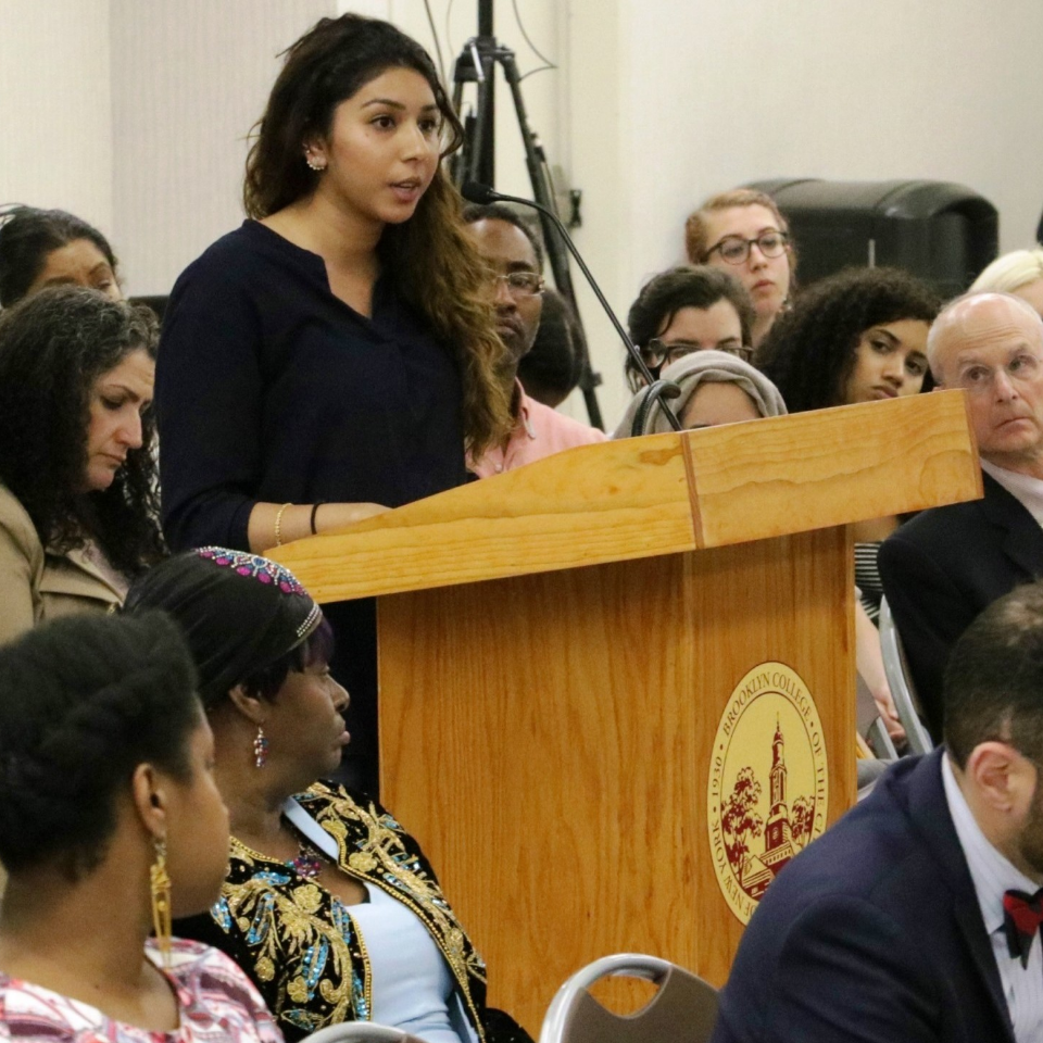 Woman speaking at podium in a crowd of people 