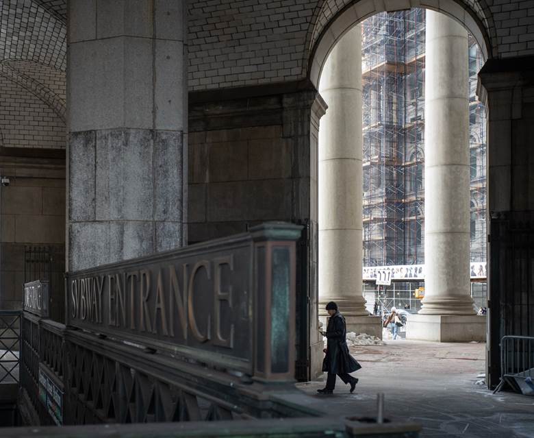 A man is walking in front of a building with a sign that says "convenience". Description generated by AI