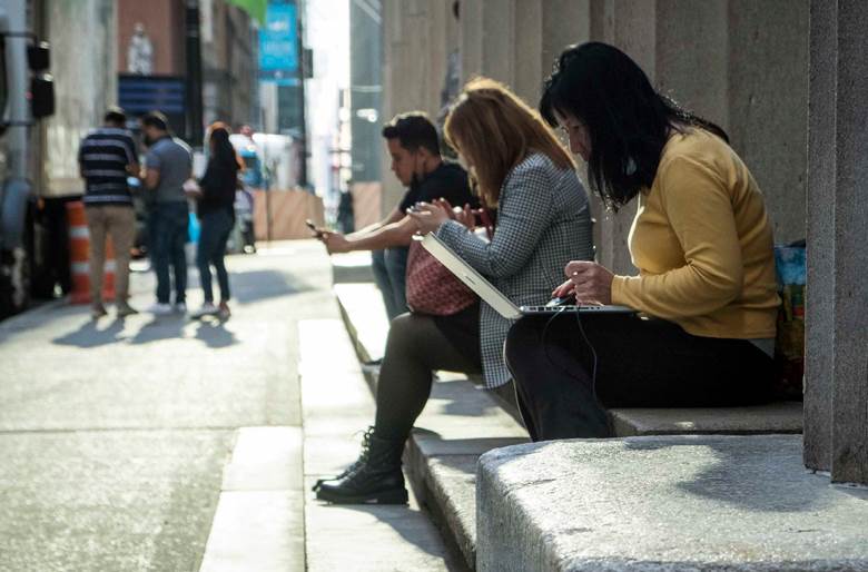 A woman sitting on a bench looking at her phone. Description generated by AI