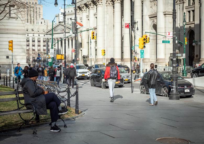 A busy city street with people walking and cars driving. Description generated by AI