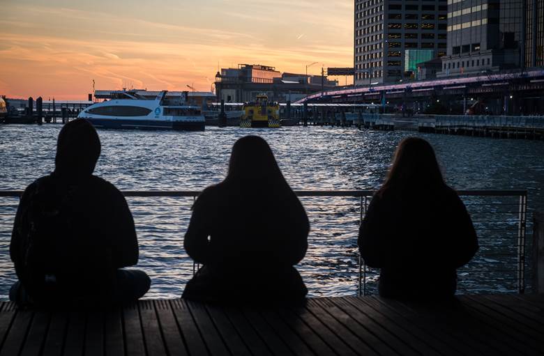 Three people sitting on a pier. Description generated by AI