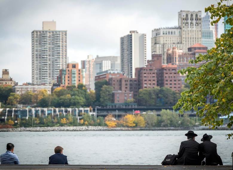 Three people sitting on a bench by a river. Description generated by AI