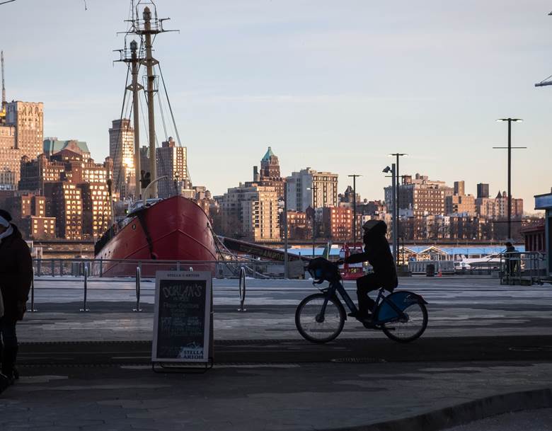 A man riding a bike in front of a large boat. Description generated by AI