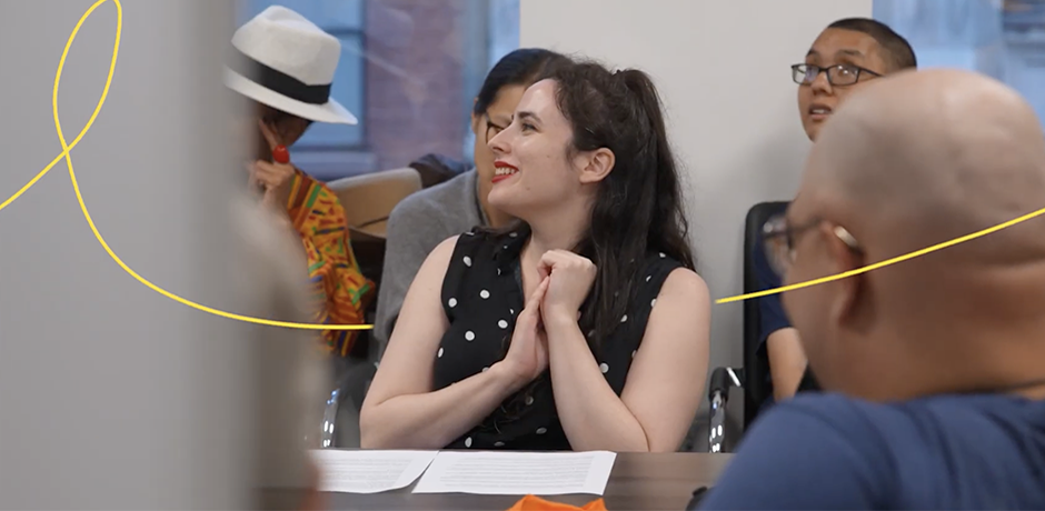 Manhattan Recap - What's in Your Borough - People seated around a meeting table indoors, smiling and listening during a community discussion.