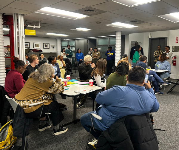 This is a photo of representatives from various community-based organizations sitting at tables at The New School as part of the community-building workshop and networking session we hosted. 