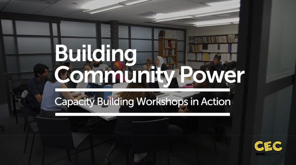 This image shows the large text Building Community Power: Capacity Building Workshops in Action, and in the background there are people sitting around a table in the middle of one of the workshops