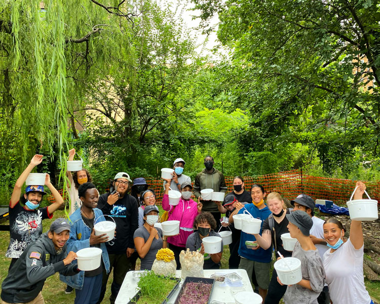 o	The photo contains many youth and some staff members from Change for Good. Youth are smiling and holding up buckets of farming supplies