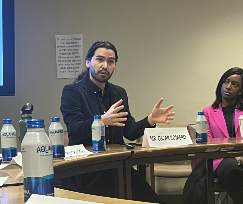 This is a photo of Oscar Romero sitting at a table while speaking on a panel.
