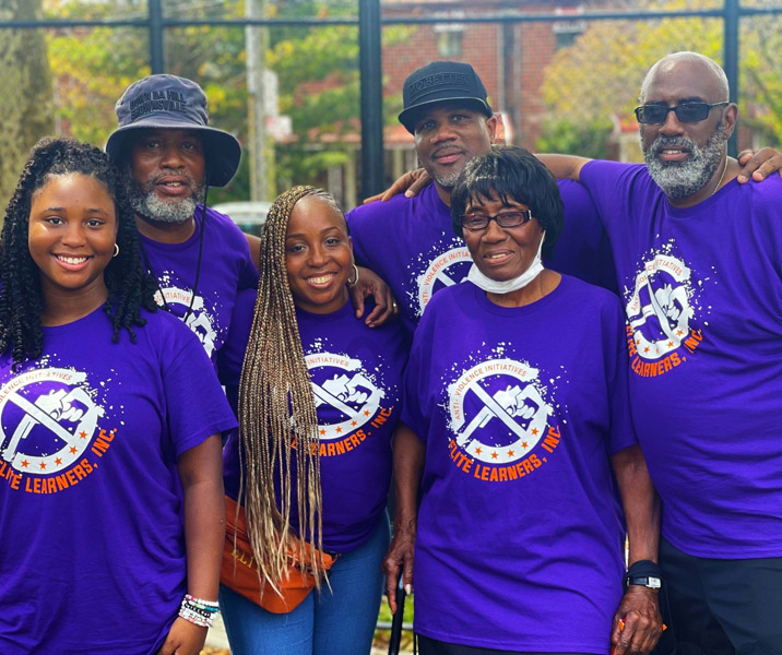 This is a photo of six people posing and smiling wearing matching dark blue shirts that say Elite Learners, Inc.