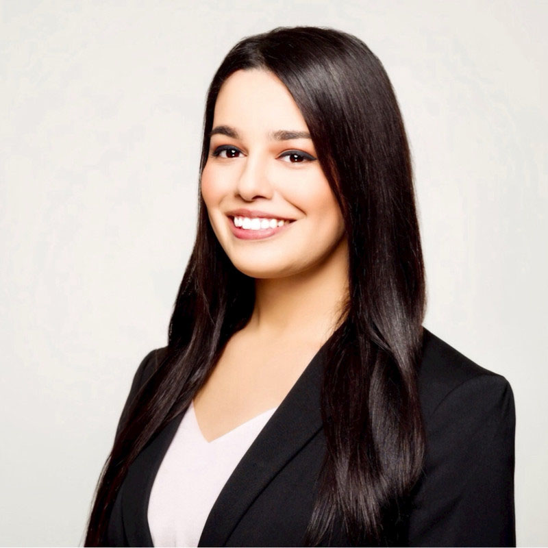 Headshot photo of Taylor Brown, a woman smiling with long dark hair wearing a white shirt and black blazer.