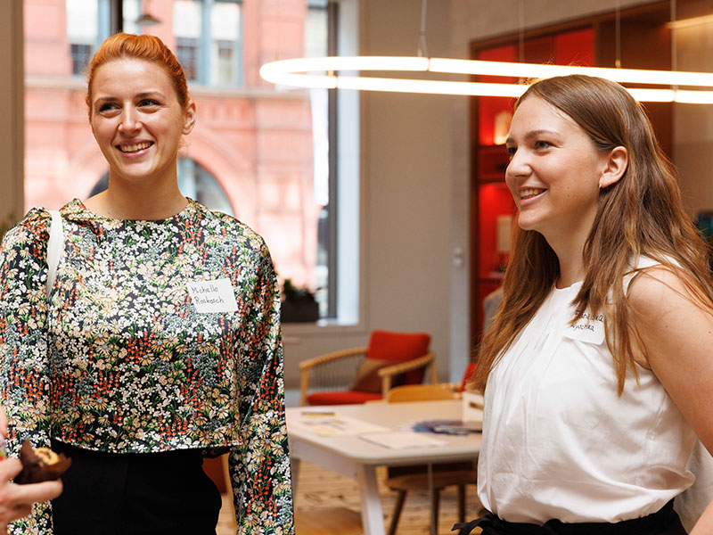 Two women engaged in a conversation with other attendees.