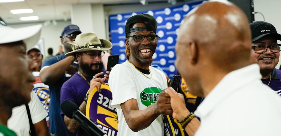 A male union worker from 32BJ SEIU shakes hands with Mayor Eric Adams in a crowd
                                           