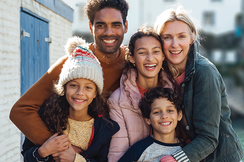 Portrait of a smiling diverse family with their arms around each other. 
                                           