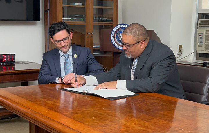 DCWP Commissioner Levine signs a document with Manhattan District Attorney Bragg.
                                           