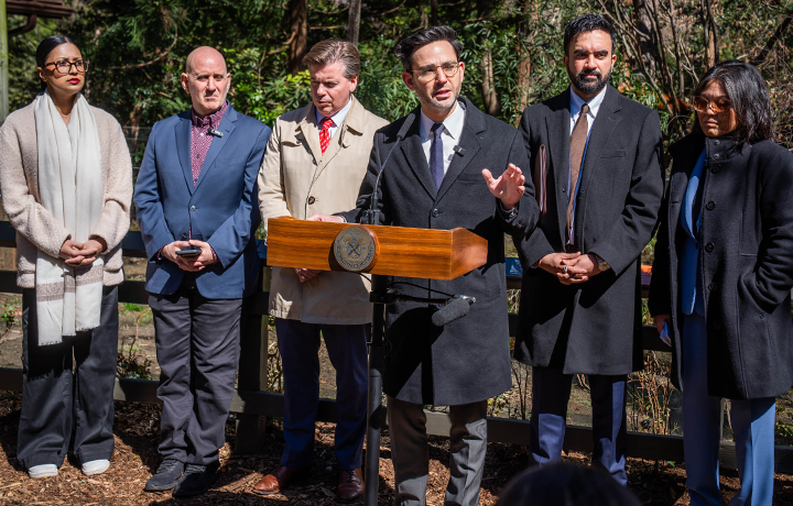 DCWP Commissioner Sam Levine speaks at podium at the Prospect Park Zoo along with Mayor Zohran Mamdani, Julie Su, Robert Carroll, Harvey Epstein, and Shahana Hanif.
                                           