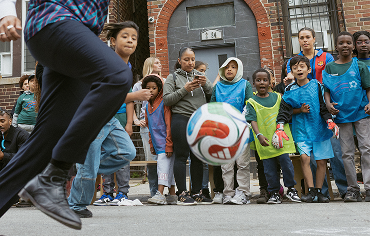 Kids watch someone kick a soccer ball
                                           