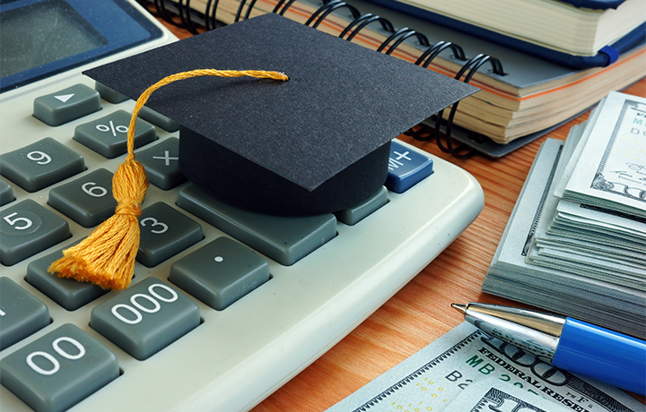 University graduation cap sits on top of $5, $50, and $100 bills
                                           