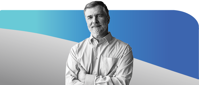 Smiling older man with gray hair and beard, arms folded