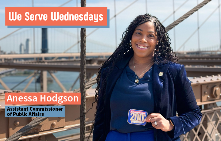 Woman with braids wearing a blue jacket walking over the Brooklyn Bridge.
                                           