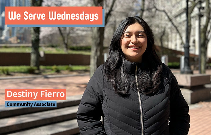 Woman standing outside on a sunny day wearing a winter coat.
                                           