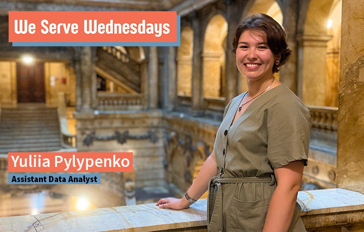 Woman stands smiling on balcony of 31 Chambers St. Marble staircase and pillars in the background.
                                           