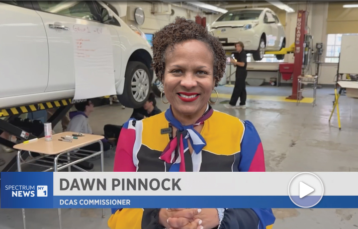 Commissioner Pinnock smiling, wearing a colorful top in front of students.
                                           