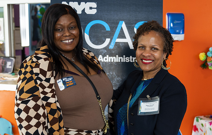 Commissioner Pinnock with woman job offer recipient in front of orange wall.
                                           