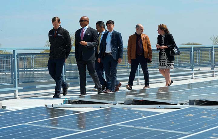 Mayor Adams walks with 4 men and a woman on a roof with solar panels.
                                           