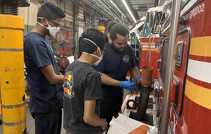 Automotive interns assisting FDNY staff member.