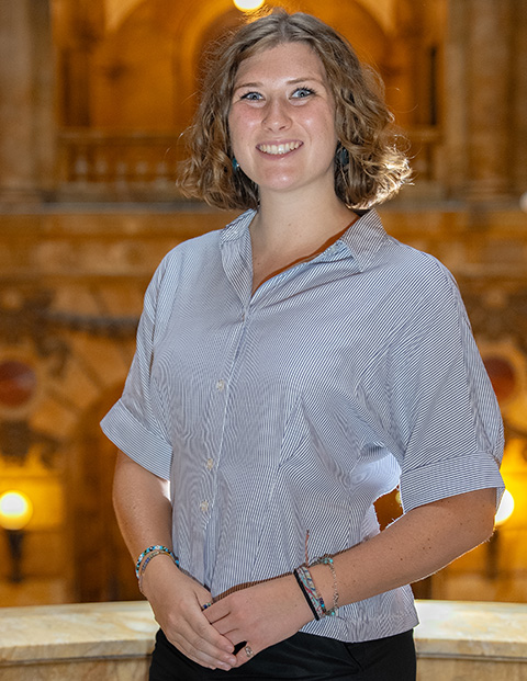 Person smiling, wearing a blue and white striped blouse and bracelets.