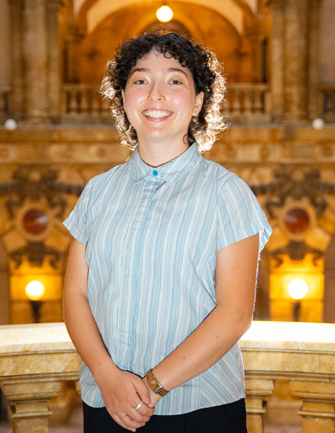 Person smiling, wearing blue and white striped shirt and a watch.