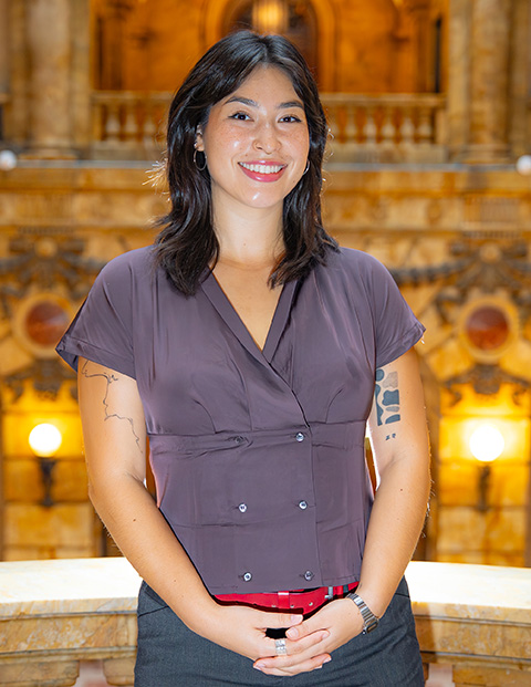 Person smiling, wearing a purple shirt and red belt.