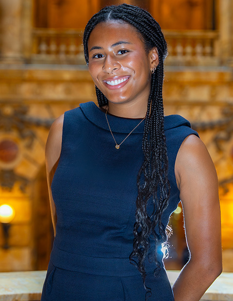 Person smiling, wearing a nacy dress and gold necklace.