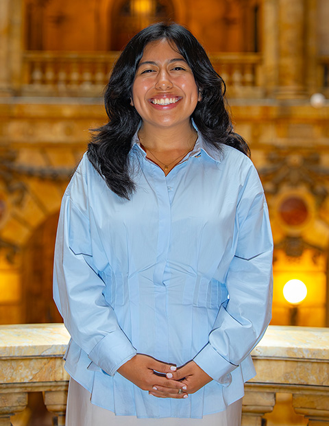 Person smiling, wearing a blue shirt and white skirt.