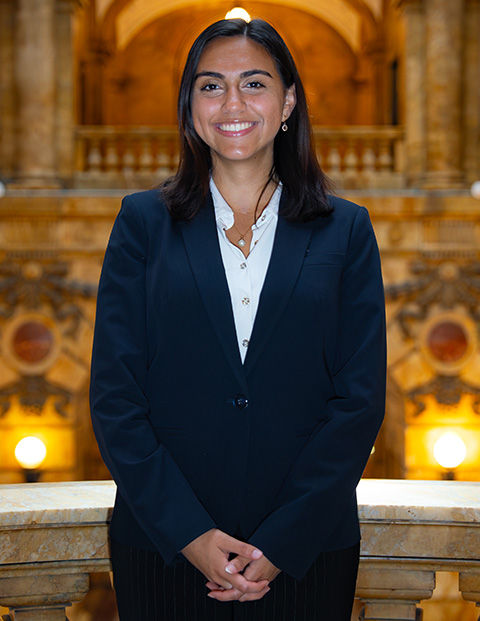 Person smiling, wearing a white button down and navy blazer.