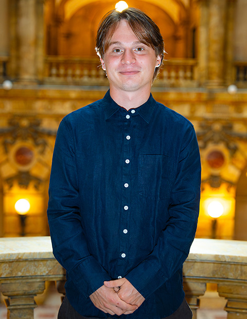 Person smiling, wearing a long-sleeved button down.