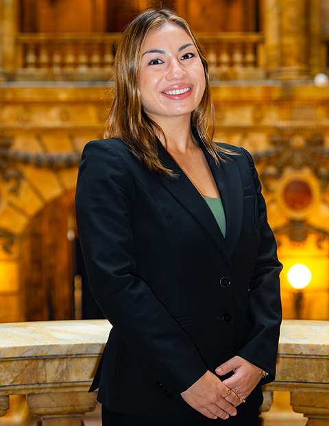 Person smiling, wearing a black blazer and green shirt.